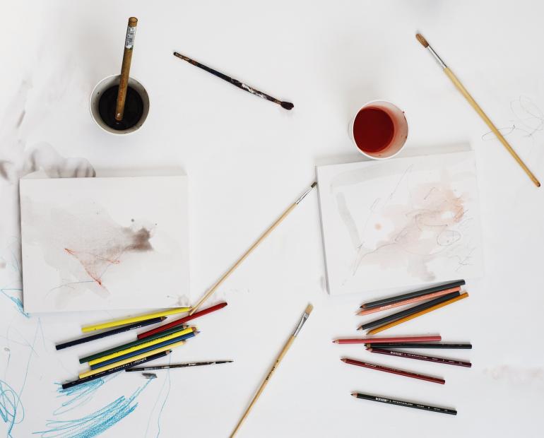 Different art supplies on a white workspace.