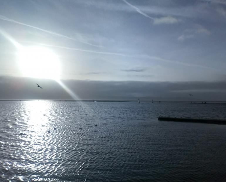 Image of the sea with the sun shining through the clouds