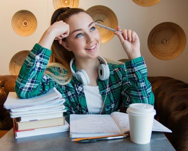 Girl happy thinking whit books,coffee,headphones and pen.