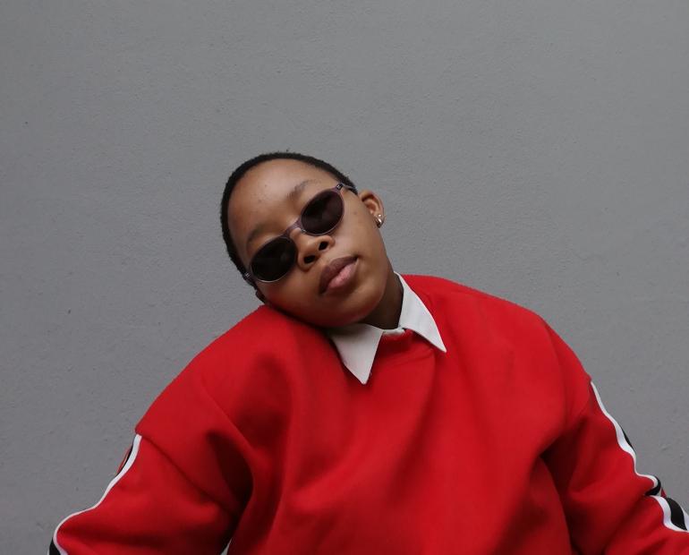 me in front of a wall looking at the camera with sunglasses and a red pullover sweater 
