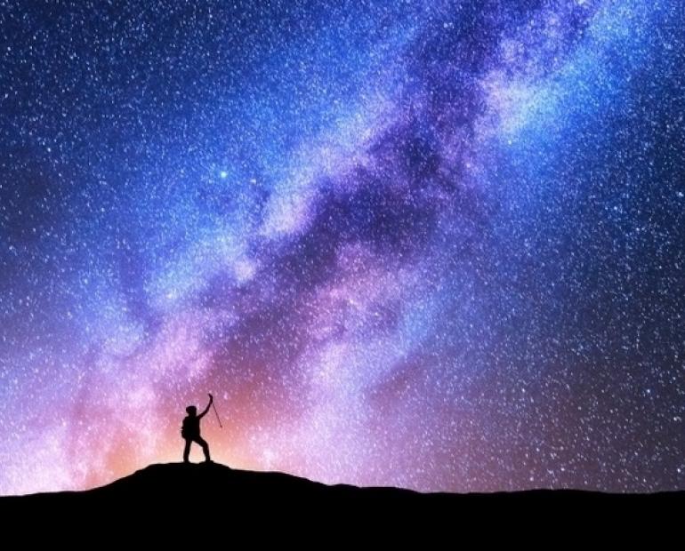 Night sky with purple, pink and blue, and the shadow of a person standing 