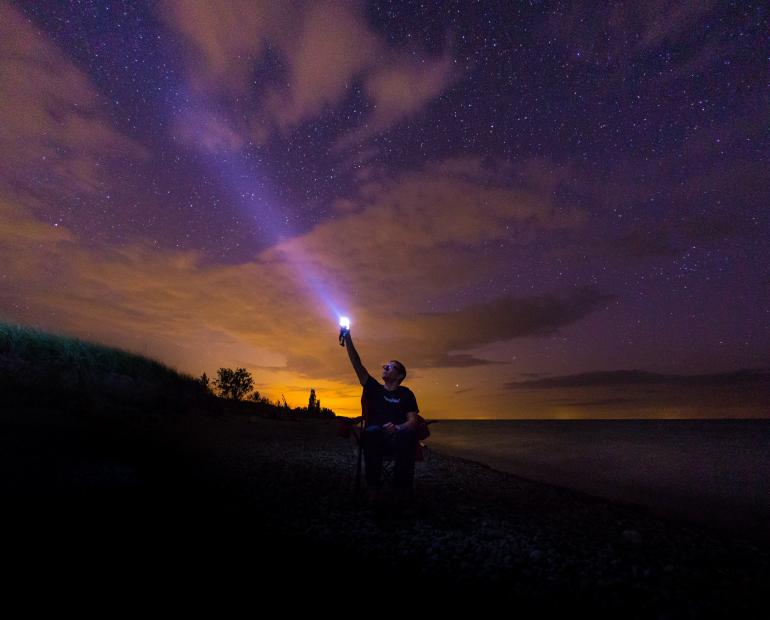 person flashing light into sky
