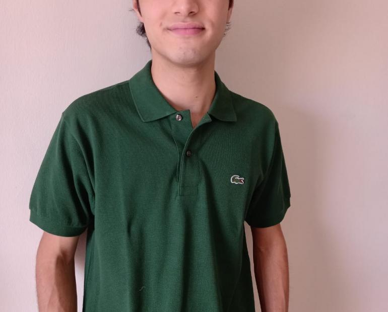 joven con camisa verde, mirando a la cámara y sonriendo