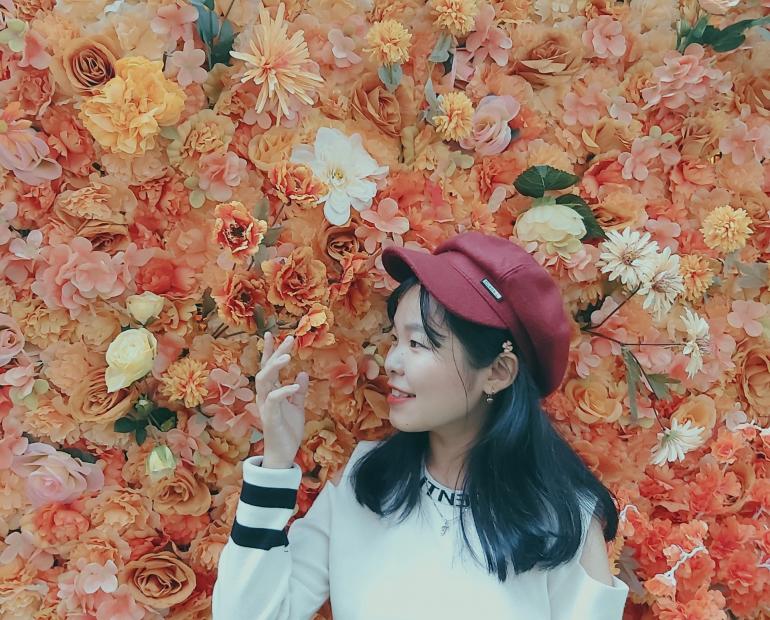 A girl stands among various flowers